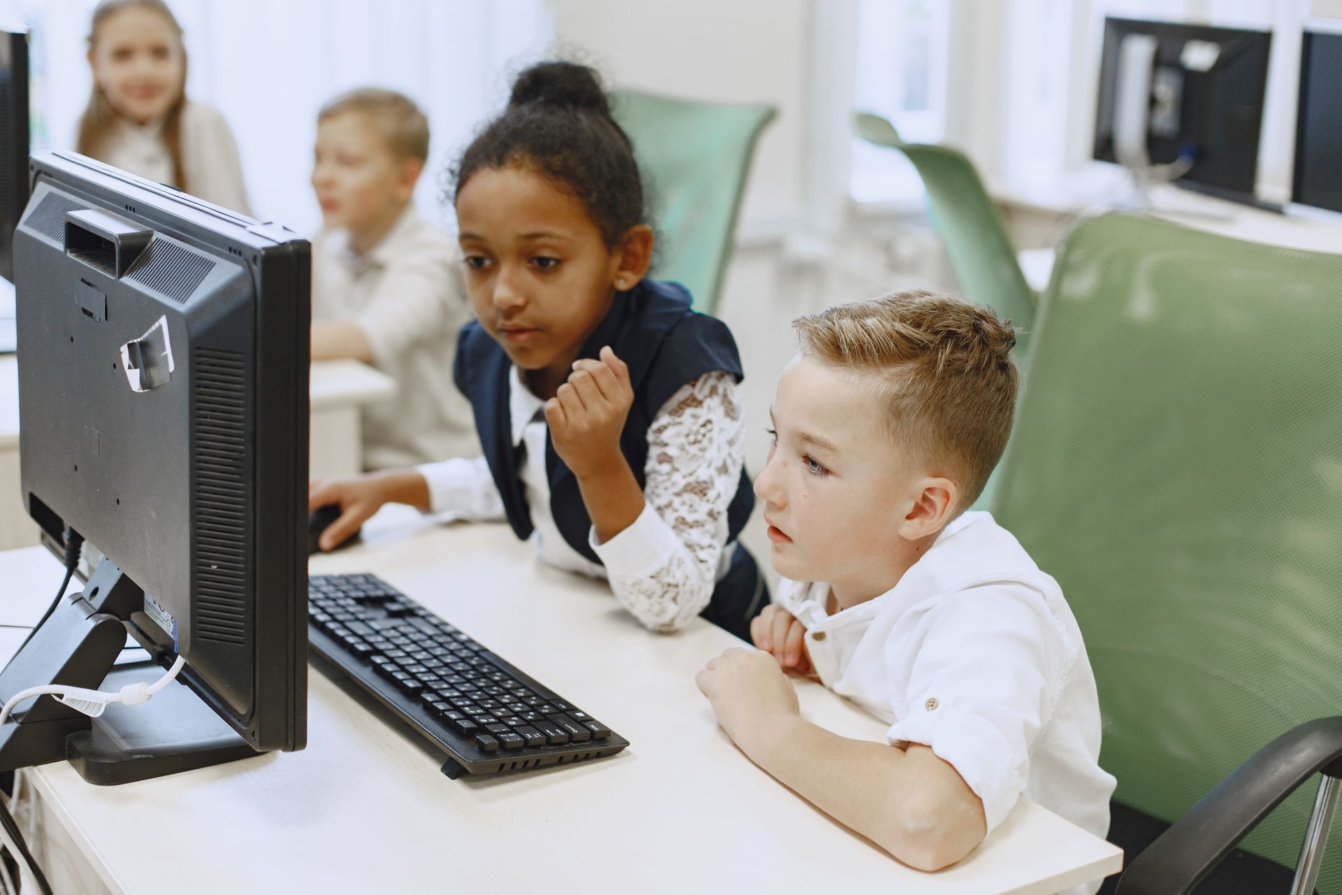 Kinder unterschiedlicher Herkunft lernen gemeinsam an Computern in einem Klassenzimmer